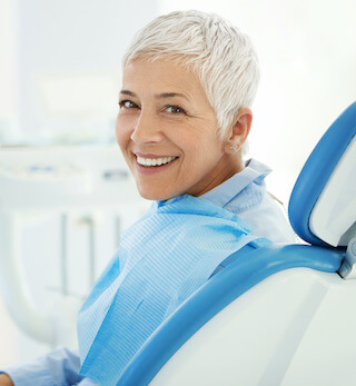 Restorative Dentistry in Boise, ID. Enjoy true wellness and a beautiful smile. Closeup over the shoulder view of a cheerful mid 50's female patient happily smiling to the camera after successful dental procedure.